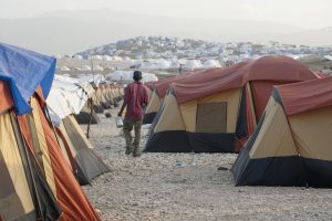 Croix-de-Bouquets, Haiti, May 01, 2010: Man is walking through the a refugee camp in the evening light. This camp is set up from differnet organisations and churches.